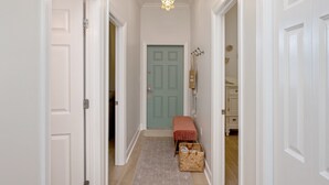 A hallway with a light blue door, a bench, and baskets on the floor. - Completely Renovated Condo- Top Floor w/ Elevator.  8 Min walk to the Beach! (Santa Rosa Beach)