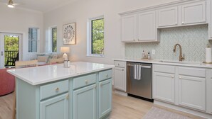 A modern kitchen with white cabinetry, a central island, and a herringbone backsplash. - Completely Renovated Condo- Top Floor w/ Elevator.  8 Min walk to the Beach! (Santa Rosa Beach)