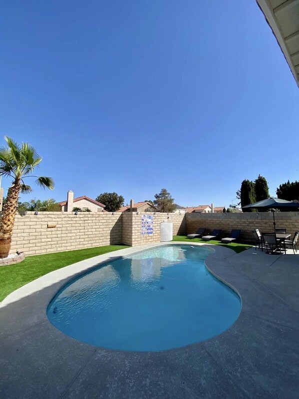 Relax by the oval-shaped pool surrounded by lounge chairs and a dining table.