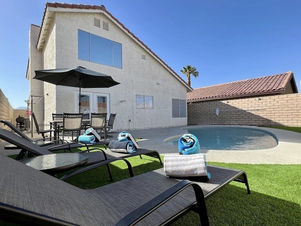 Una casa con piscina, muebles de exterior y un patio.