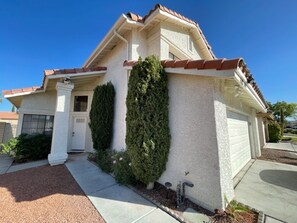 Stucco house with a red-tiled roof, featuring a single-story design and a welcoming entrance with a white door and window.