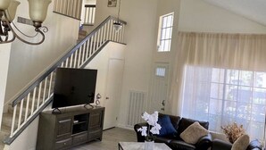 A spacious living room with a staircase, a flat-screen TV, leather sofas, and a marble coffee table. - Cheerful 3-Bedroom home w/ Pool(minutes to the Strip) (Las Vegas)