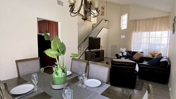 A dining area with a chandelier, a potted plant, and a staircase leading to a living room. - Cheerful 3-Bedroom home w/ Pool(minutes to the Strip) (Las Vegas)