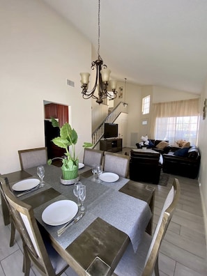 Enjoy meals in this inviting dining area with a central plant, staircase, and large window.