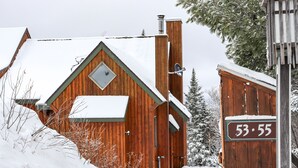 A wooden cabin with a snow-covered roof and a chimney. - Rock Pond Condo 53 - Ski in Ski out Rock Pond Condo at Saddleback (Rangeley)