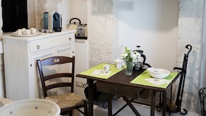 Una habitación rústica con paredes de piedra, una chimenea, una mesa de comedor con sillas y un rincón para café.