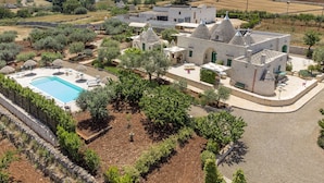 Una villa con piscina, mobiliario de exterior y jardín.
