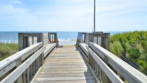 Eine Holzpromenade führt zu einem Strand mit freiem Blick auf den Ozean.