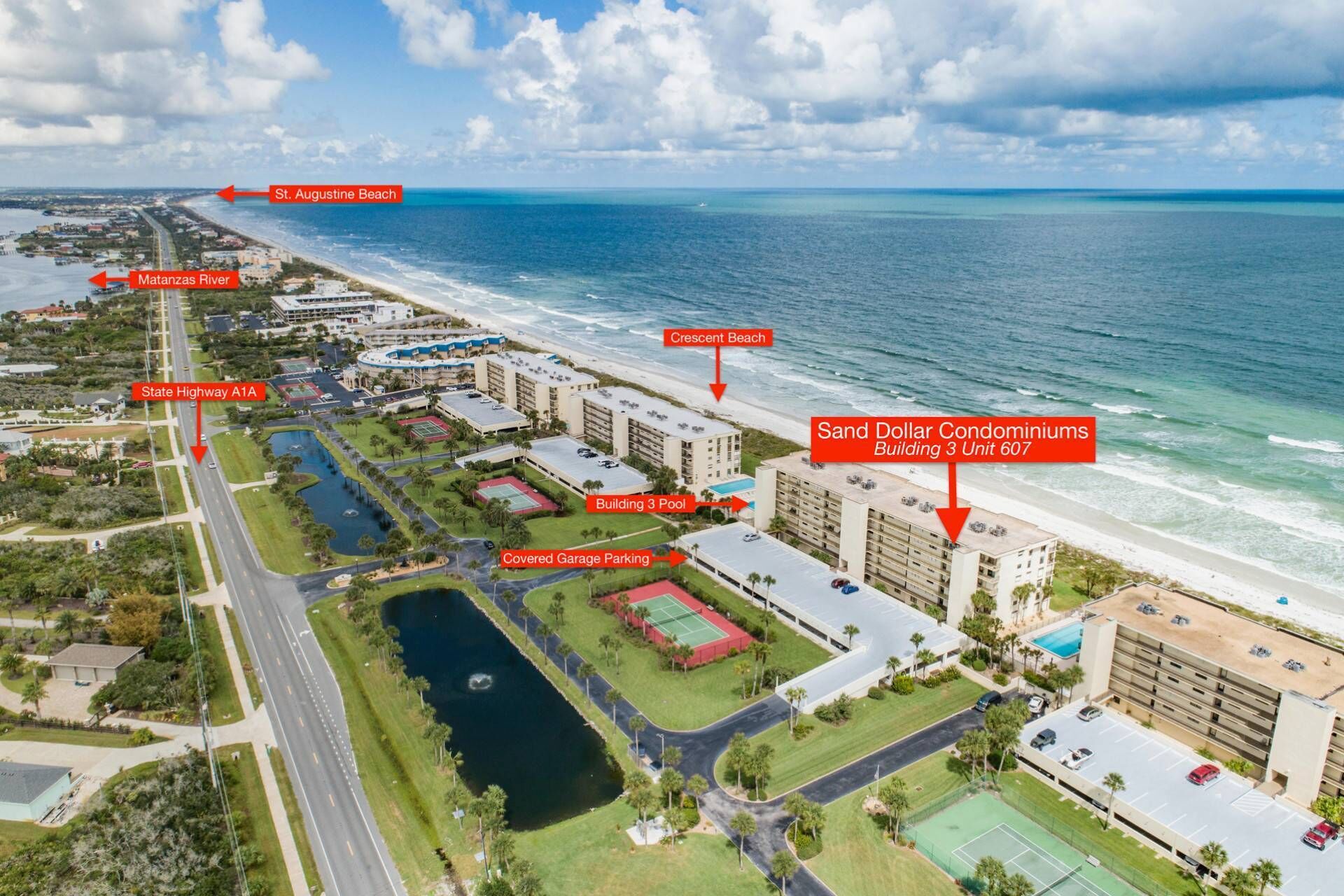Oversigtsbillede af et kystområde med Sand Dollar Condominiums Bygning 3 Enhed 607, der viser en swimmingpool, overdækket parkering og nærhed til St. Augustine Beach og Crescent Beach.