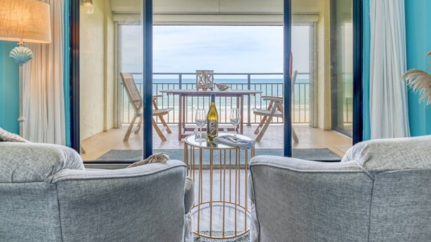 Ein Balkon mit Tisch, Stühlen und einer Weinflasche mit Blick auf das Meer.