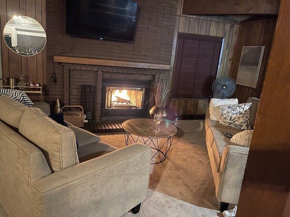 Una sala acogedora con chimenea, televisor montado en la pared y asientos cómodos.
