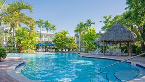 Une piscine dont la profondeur est indiquée à 3 pieds, entourée de palmiers et de chaises longues.