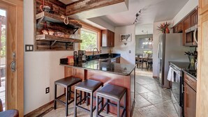 A modern kitchen with wooden accents, a central island, and bar stools.