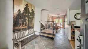 A spacious hallway with a wooden bench, a staircase, and a large wall mural.