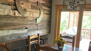 A wooden dining table with chairs, a vase of yellow flowers, and a rustic wall with a crescent moon decoration.