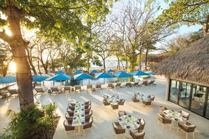 An outdoor dining area with tables and chairs, surrounded by trees and umbrellas. - Looking for a paradise destination? Casa Tres Monos is ready to welcome you. (Peninsula Papagayo)