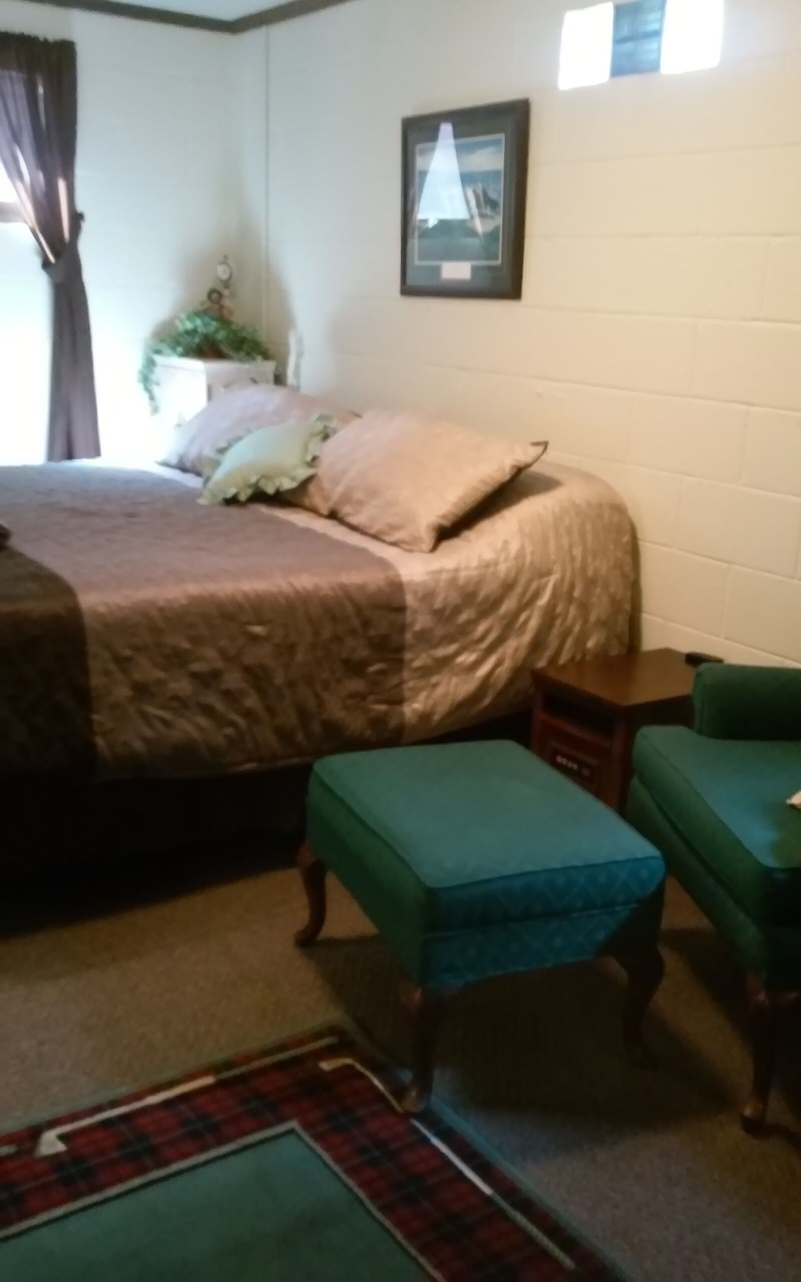A bedroom with a bed, a small table, a bench, and a picture on the wall.