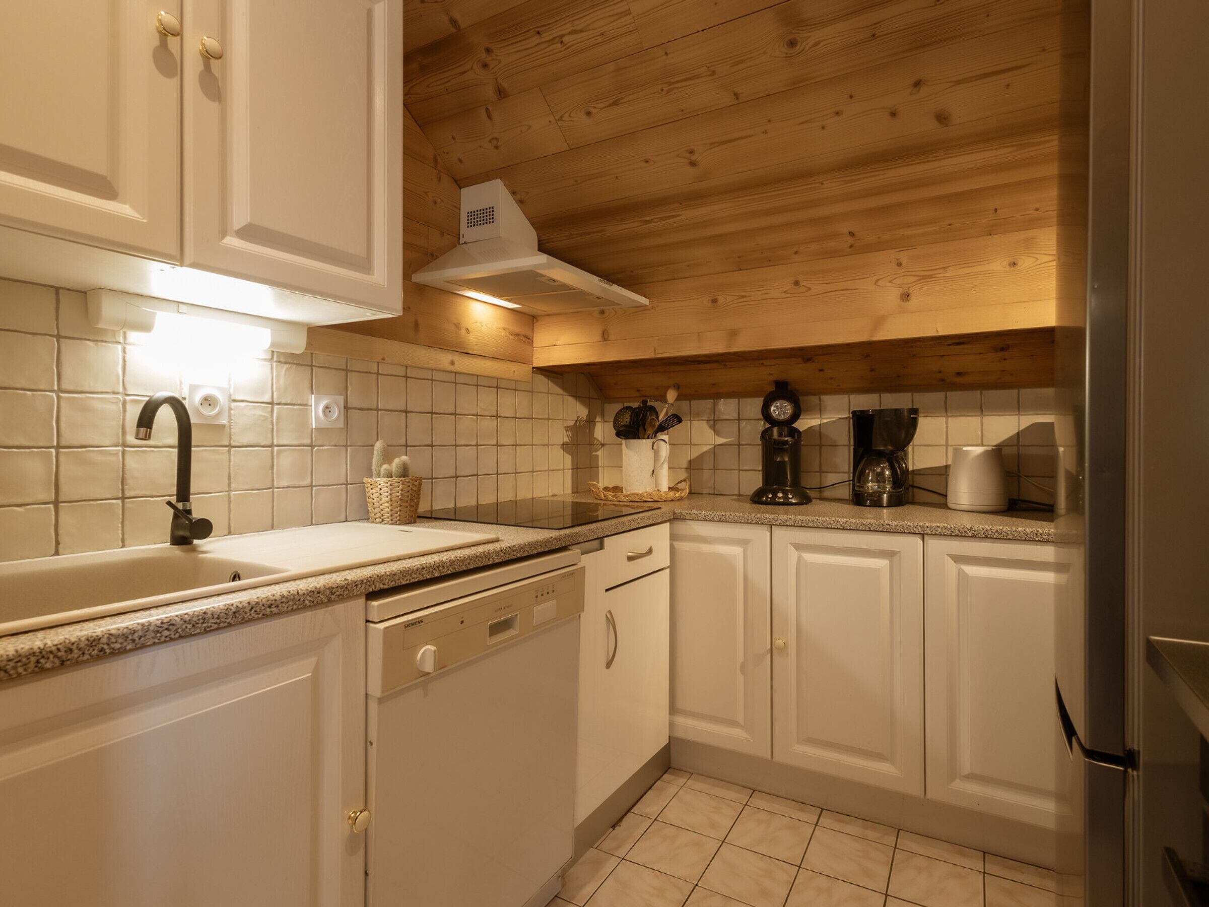 A kitchen with white cabinets, a sink, a stove, and a coffee maker.