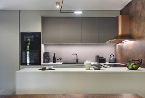 A modern kitchen with a built-in microwave, a coffee maker, and a kettle on the counter.