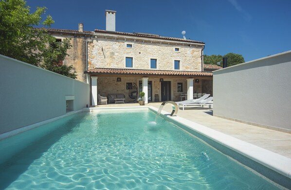 A swimming pool with a stone building in the background.