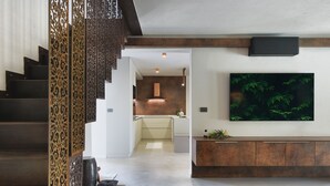 Un interior moderno con una escalera, una cocina y un televisor de pantalla plana grande montado en la pared.