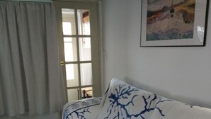 A room with a white sofa with blue tree patterns, a window with white curtains, and a framed painting on the wall. - La Casita Azul 1. Your corner in the country. (La Estación de Puerto Lumbreras)