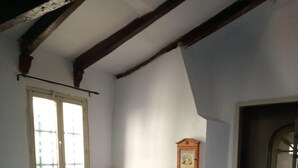 A room with a tiled floor, a bench with a patterned cover, a red lamp, a fireplace with a wooden mantel, and a door leading to another room. - La Casita Azul 1. Your corner in the country. (La Estación de Puerto Lumbreras)