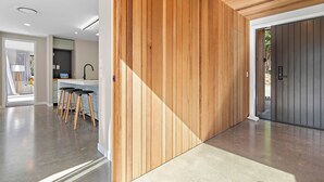 Eine moderne Küche mit Holzelementen, eine Bar mit Hockern und Blick ins Freie.