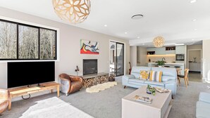 Ein modernes Wohnzimmer mit einem großen Flachbildfernseher, einem Kamin und einem hellblauen Sofa.