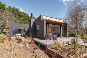 Una casa moderna con un portico coperto, un camino e un giardino ricco di piante.