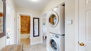 Une buanderie équipée de deux machines à laver à chargement frontal superposées, de toilettes et d’un espace douche.