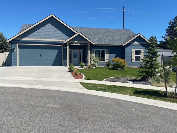 A two-story house with a garage, a front porch, and a well-maintained lawn.
