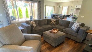 Ein Wohnzimmer mit einem Ecksofa, einem kleinen Hocker und einem Holztisch.
