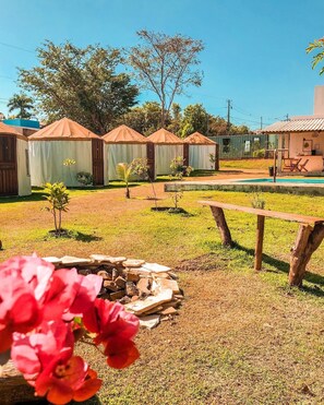 Un terrain de camping avec des tentes, un foyer et une piscine.