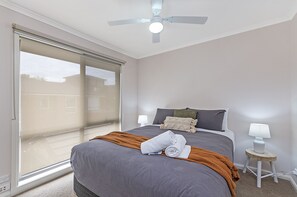 Relax in this serene bedroom with a large bed, ceiling fan, and sliding glass door.