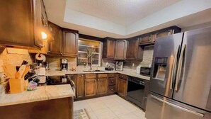 A kitchen with wooden cabinets, a stainless steel refrigerator, and a coffee maker. - DIRECT Gulf View/Access! KAYAKS!!! WATERFRONT!!! (Hernando Beach)