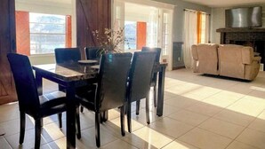 A dining area with a table and chairs, a fireplace, and a sofa in a well-lit room with large windows. - DIRECT Gulf View/Access! KAYAKS!!! WATERFRONT!!! (Hernando Beach)