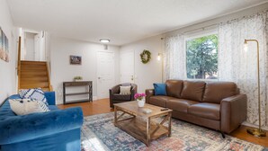 A living room with a blue sofa, a brown leather couch, a wooden coffee table, and a patterned rug. - Newly Renovated-Spacious-20min to Den& Boulder-HotTub/Game Room/Basketball Court (Westminster)