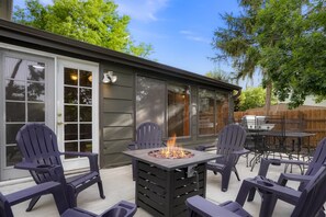 En udendørs terrasse med Adirondack-stole, pejse og grillområde.