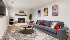 A living room with a grey sofa, a fireplace, a mounted TV, and a large rug. - Newly Renovated-Spacious-20min to Den& Boulder-HotTub/Game Room/Basketball Court (Westminster)