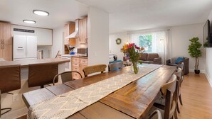 A modern kitchen with wooden cabinets, a built-in oven, and a dining area with a long wooden table and chairs. - Newly Renovated-Spacious-20min to Den& Boulder-HotTub/Game Room/Basketball Court (Westminster)