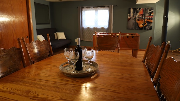 Une salle à manger avec une table en bois dressée pour six personnes, entourée de chaises.