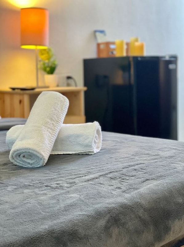 A neatly folded white towel on a textured gray bedspread in a hotel room.