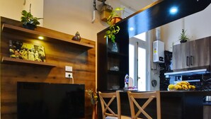 A modern kitchen with wooden cabinetry, a built-in TV, and a dining area with two chairs. - The Place 3 charming downtown apartment Cairo (Cairo Governorate)