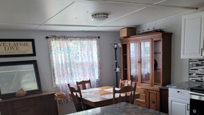 Uma cozinha com bancada de mármore, armários de madeira, uma mesa de jantar com cadeiras e iluminação embutida no teto.