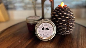 A wooden table with a candle, a pine cone, and two jars.