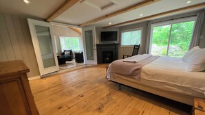 A spacious bedroom with a large bed, a fireplace, and a television. - Bright and spacious lakeside cottage with firepit, hot tub and AC on Stoney Lake (Lakefield)