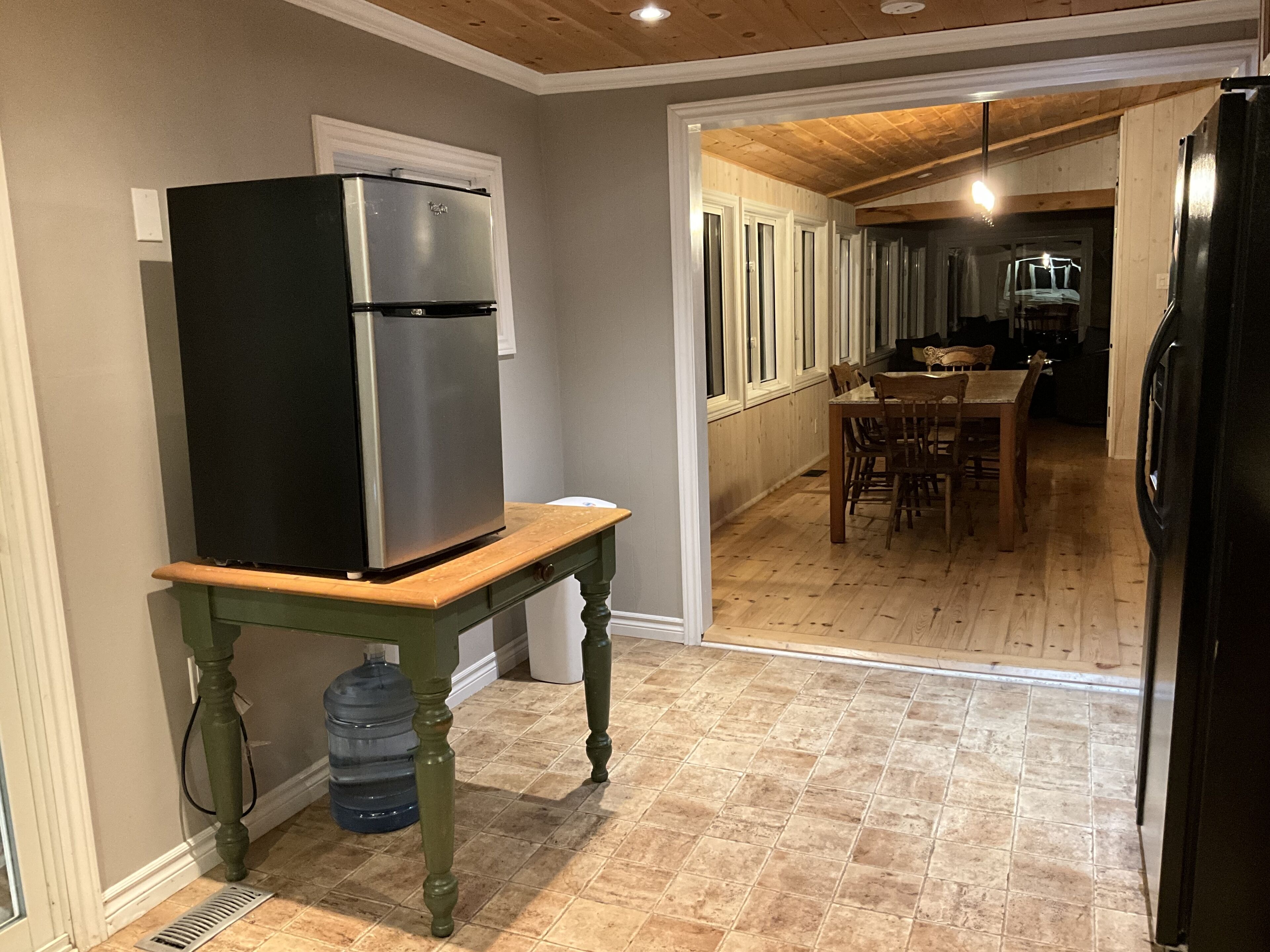 A kitchen with a refrigerator, a water dispenser, and a wooden table.