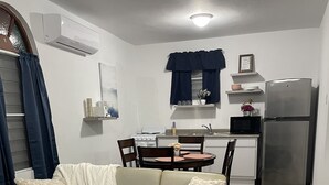 Un salon comprenant un canapé, une table à manger, des chaises, et un coin cuisine équipé d’une cuisinière, d’un four à micro-ondes et d’un réfrigérateur.