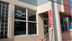 Un bâtiment avec une fenêtre sur laquelle est affiché le nom « Zarat » et une enseigne indiquant « Beauté et spa ».
